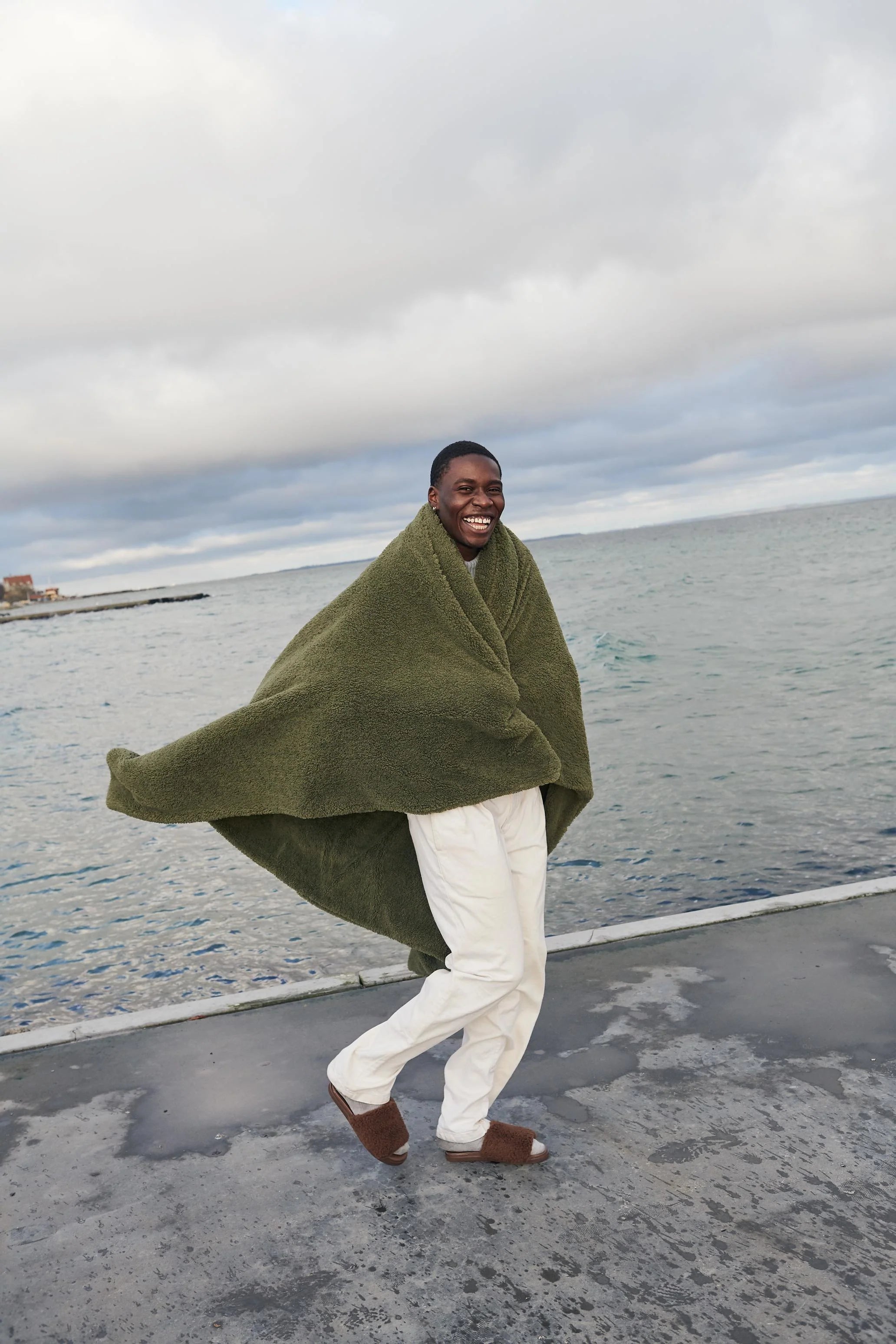 guy walking around on beach with blanket around him