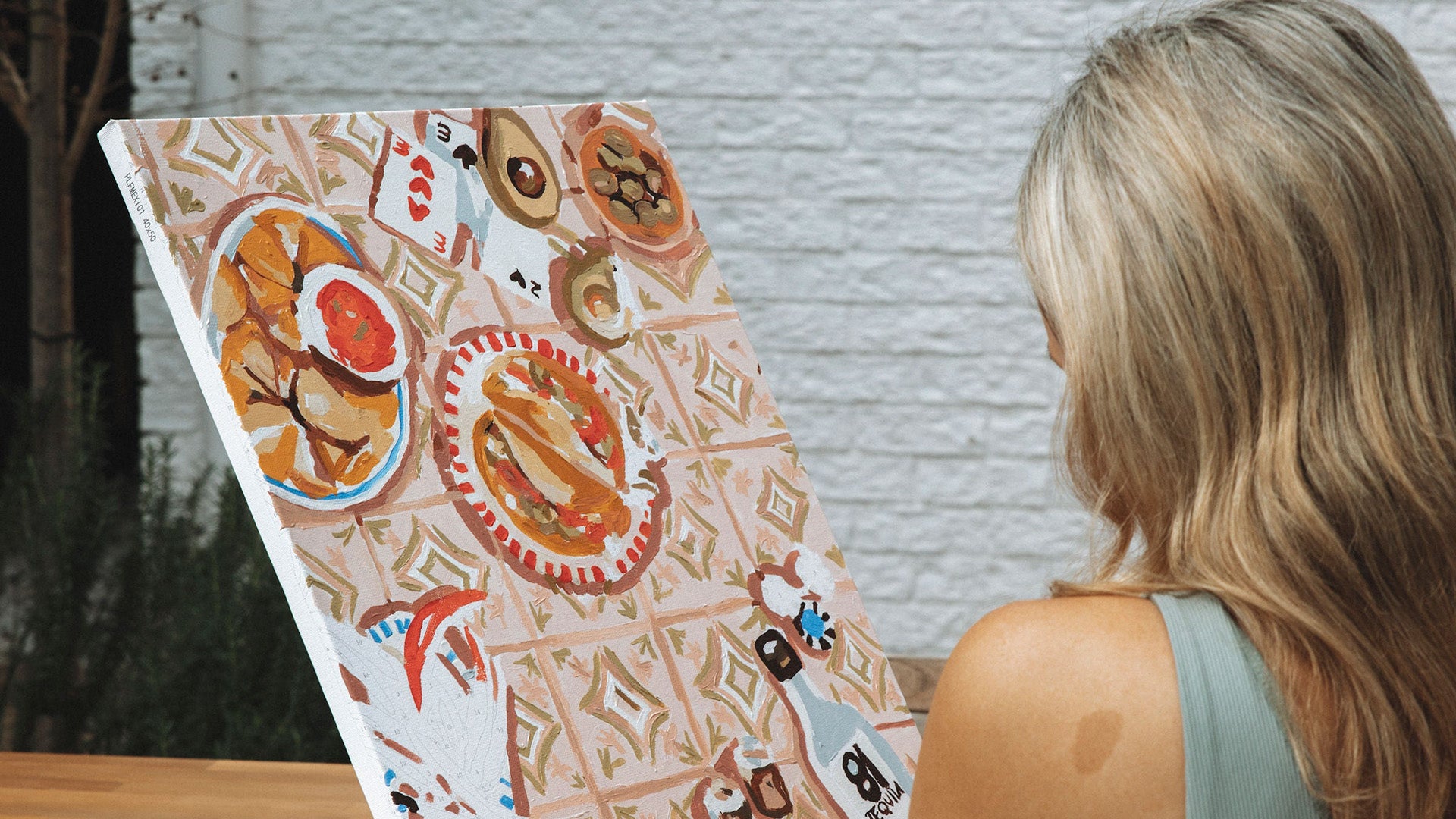 girl sitting down in front of an artwork she is painting