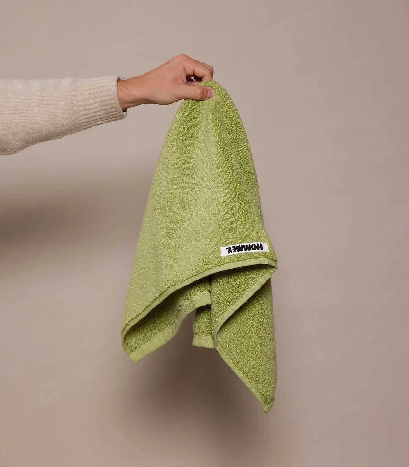 girl holding up green hand towel