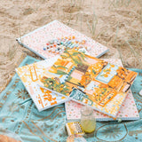 paint by numbers kits sitting on a picnic blanket on a beach