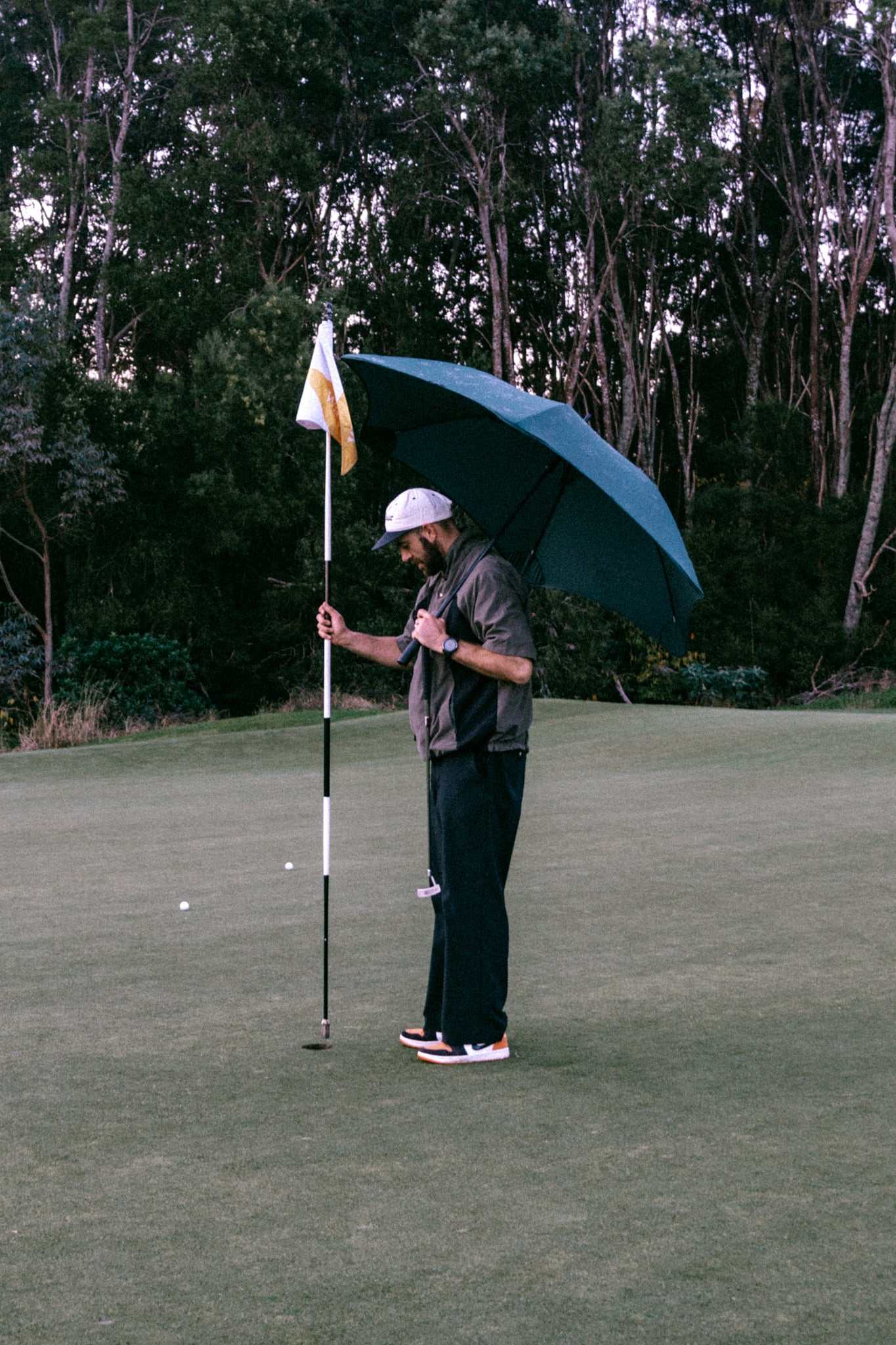 man with umbrella on gold course