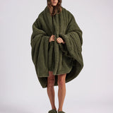 woman standing with green fluffy throw blanket around her