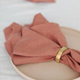 rose pink napkin with a gold napkin ring around it