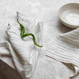 Striped olive linen table napkin set made from 100% European flax with fine hem finish on marble surface