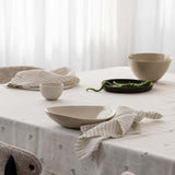 tablescape of a table with napkins, ceramics, tablecloth on it