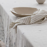 striped linen napkin sitting on a table with a tablecloth on it