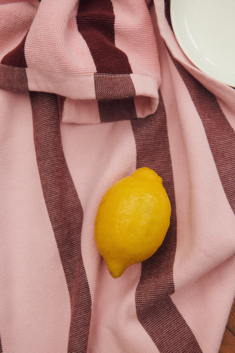 striped pink and red tea towel on floor with lemon