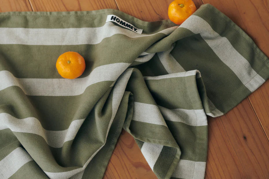 green and grey striped tea towel on floor with mandarins