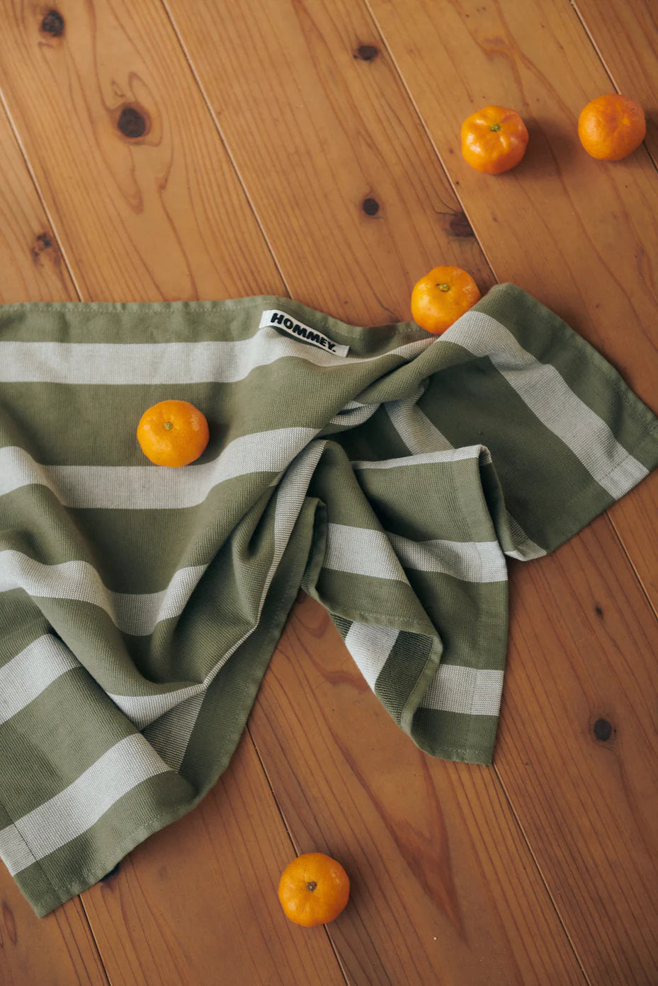 green and grey striped tea towel on floor with mandarins