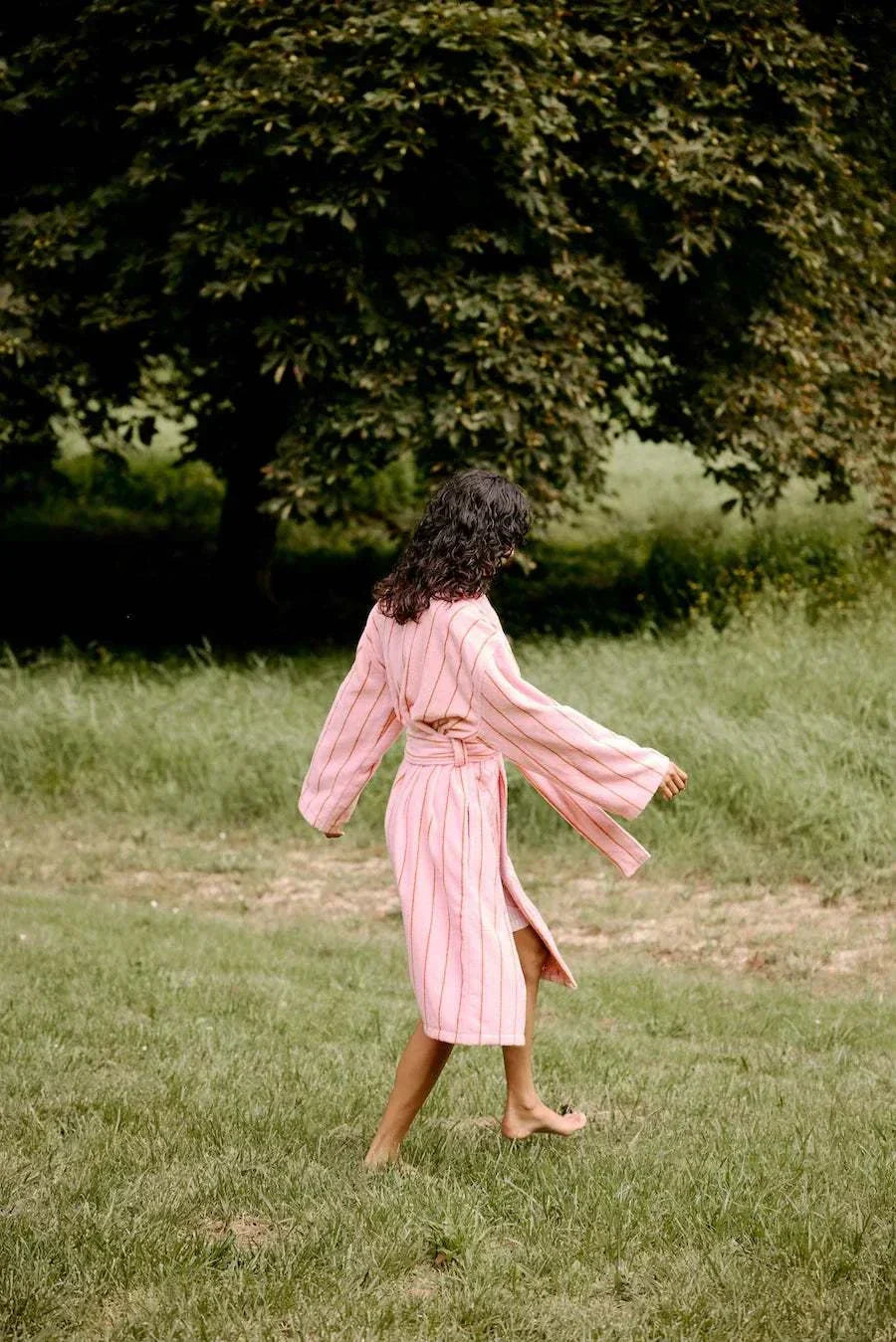 woman walking in field in bath robe 