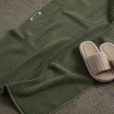 shoes next to dark green bath mat 