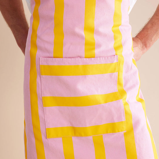 close up shot of guy standing in pink and yellow striped apron 