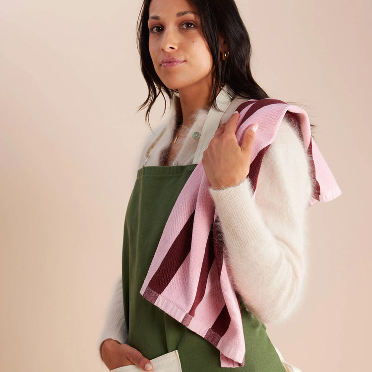 woman has striped pink and red tea towel slung over her shoulder 