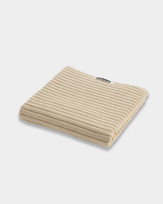 beige bath mat sitting on white background