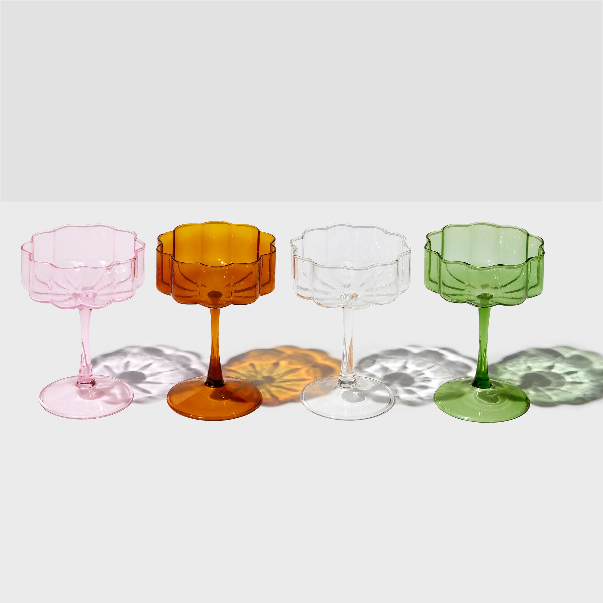 different coloured wave coupe glasses sitting on white table