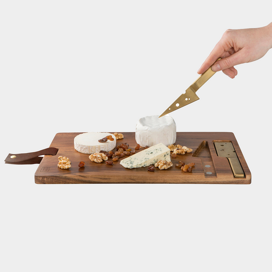 cheese board with cheese laid out and someone slicing cheese