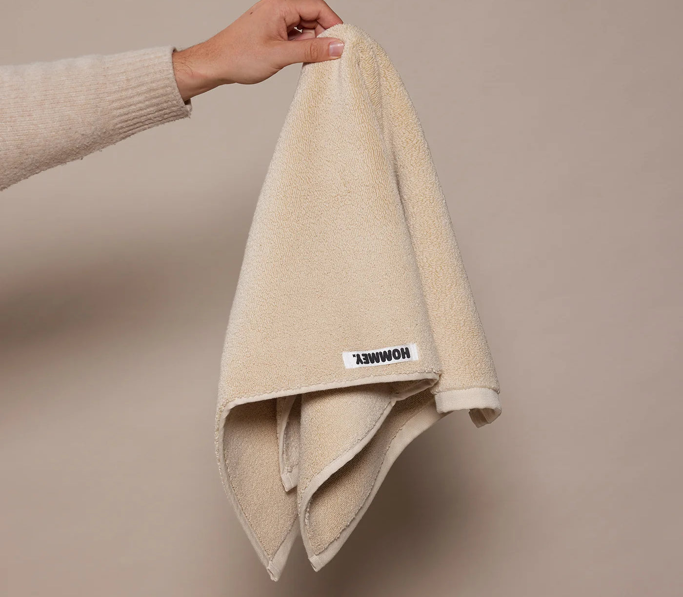 beige face washer towel being held up by woman