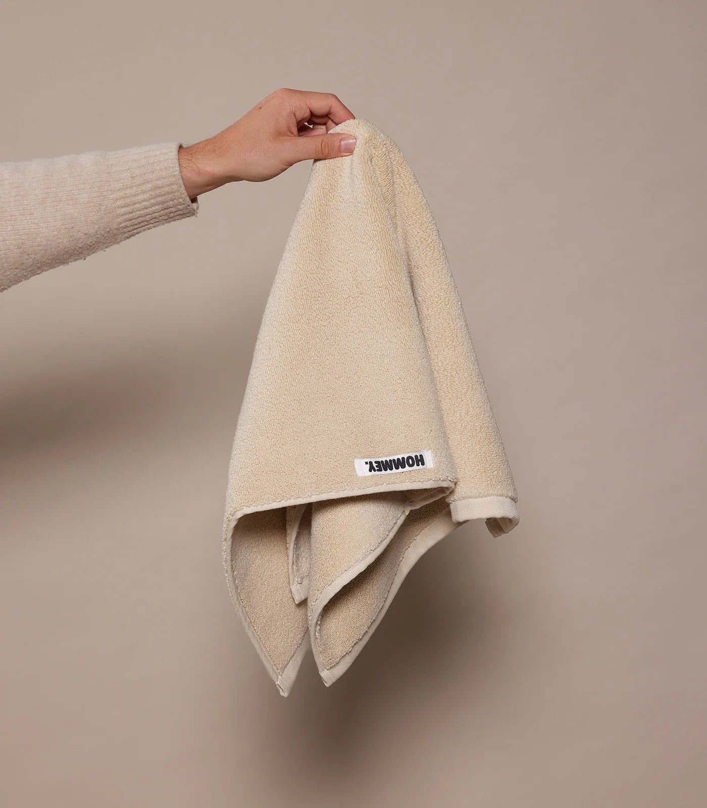 beige face washer towel being held up by woman