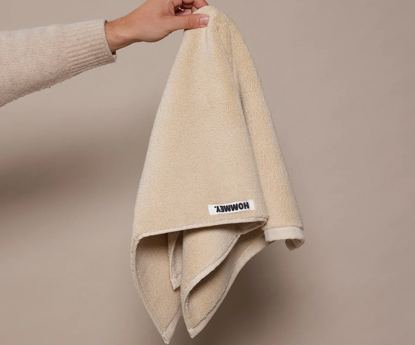 woman holding up beige towel