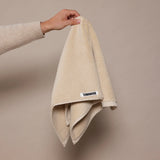 woman holding up beige towel