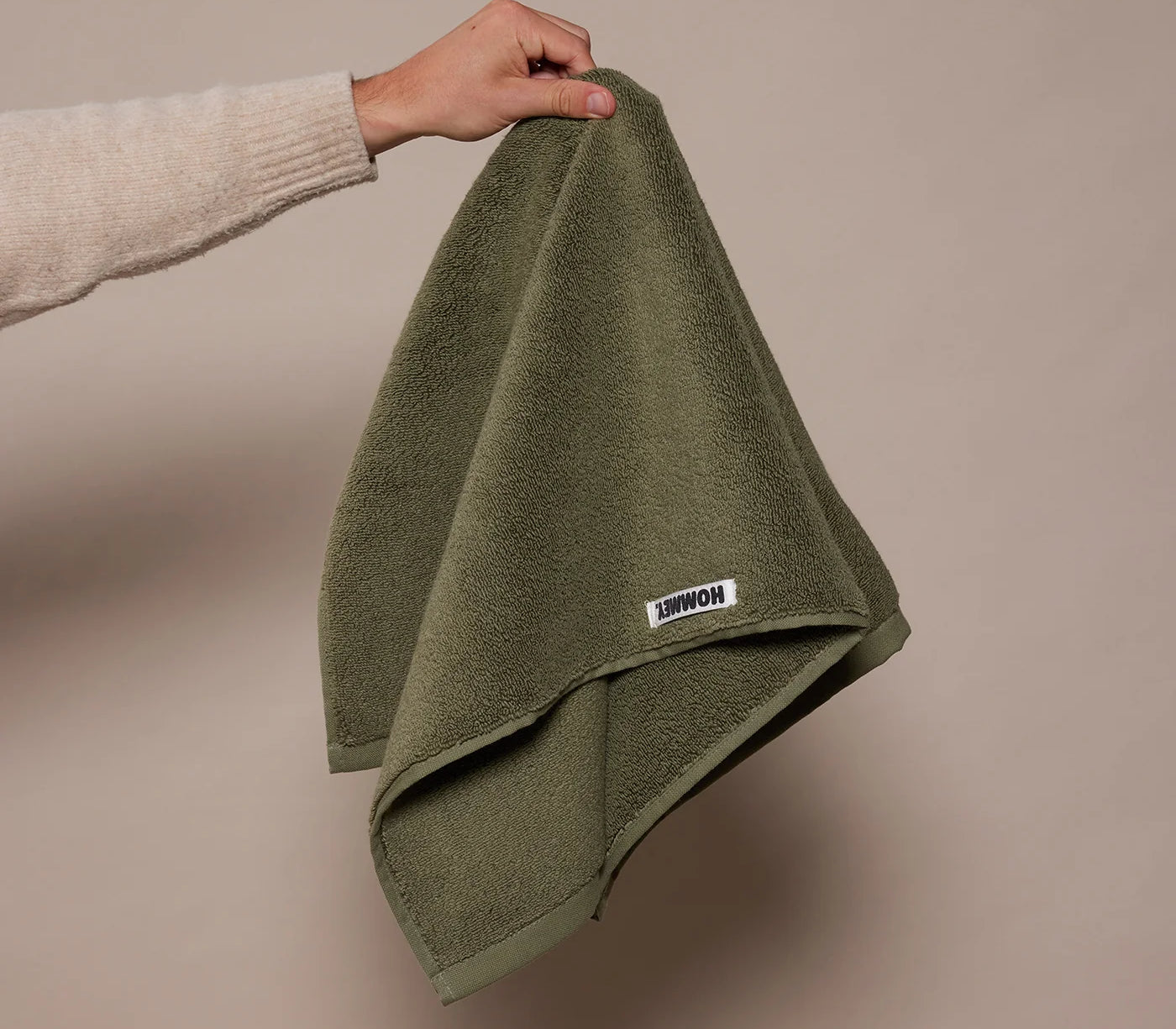 woman holding up dark green towel