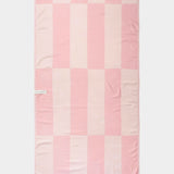 pink and white beach towel laid out flat