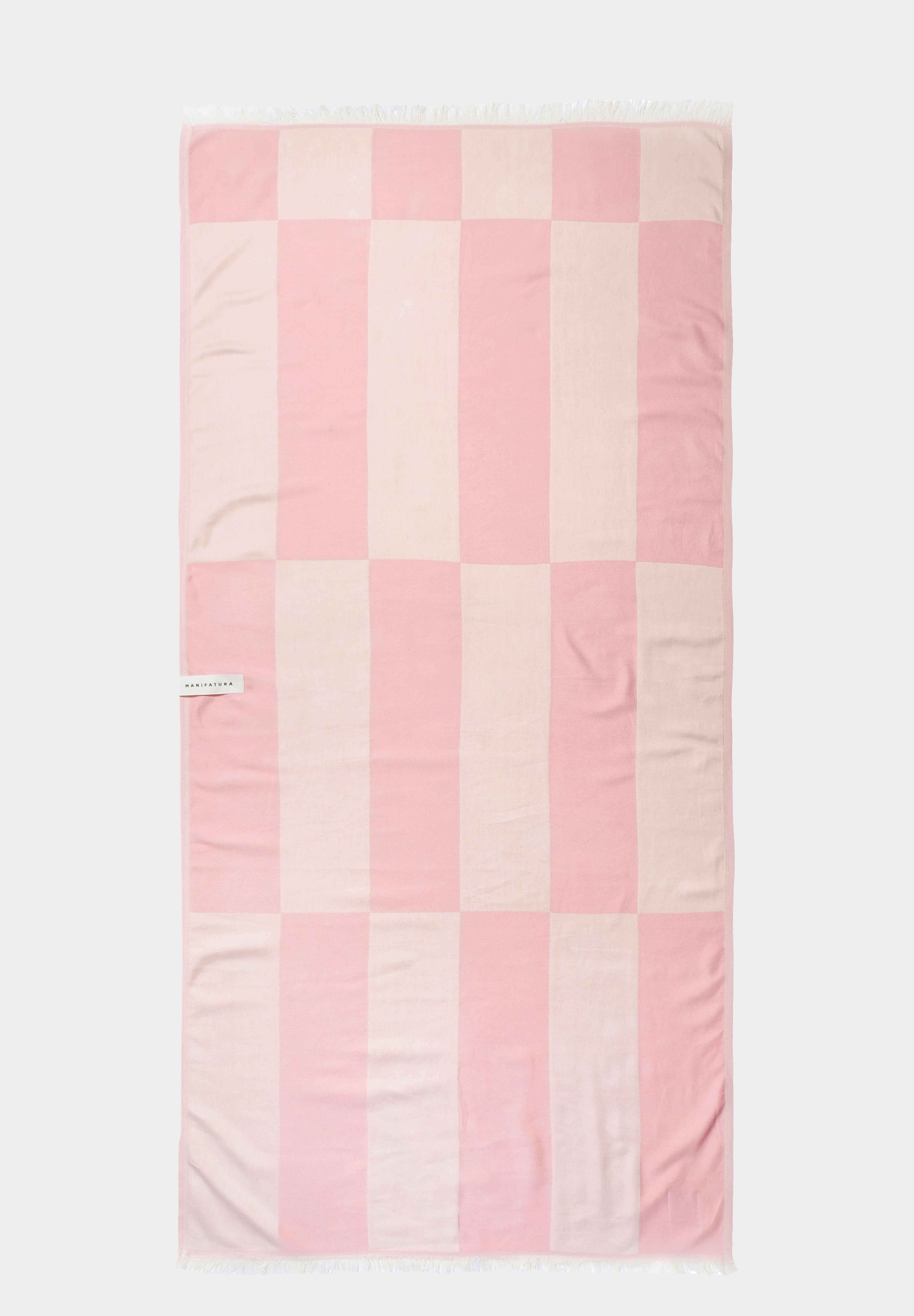 pink and white beach towel laid out flat