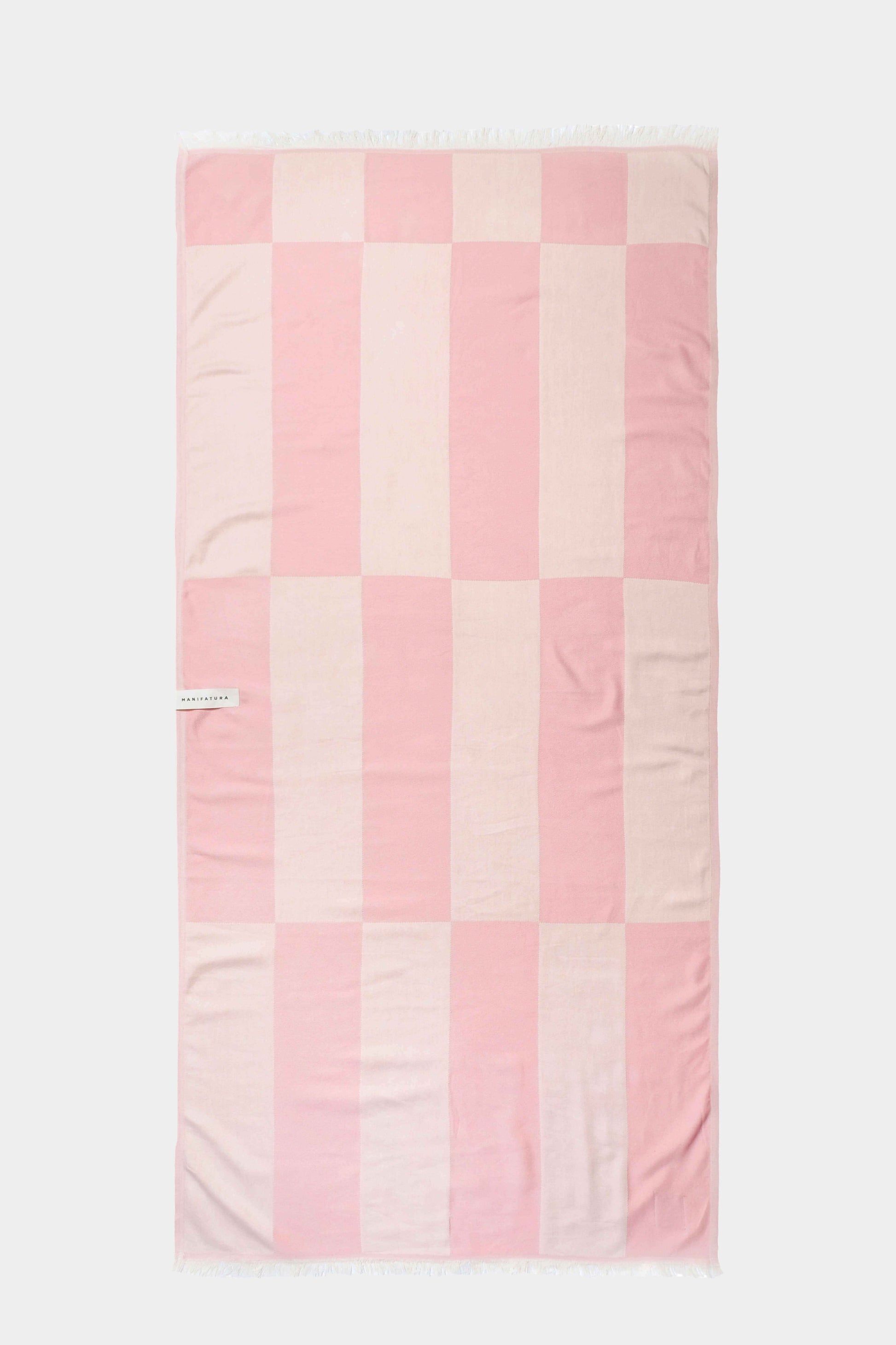 pink and white beach towel laid out flat