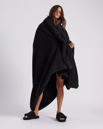 woman standing with black fluffy throw blanket around her