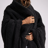 woman standing with black fluffy throw blanket around her