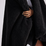 up close shot of woman standing with black fluffy throw blanket around her