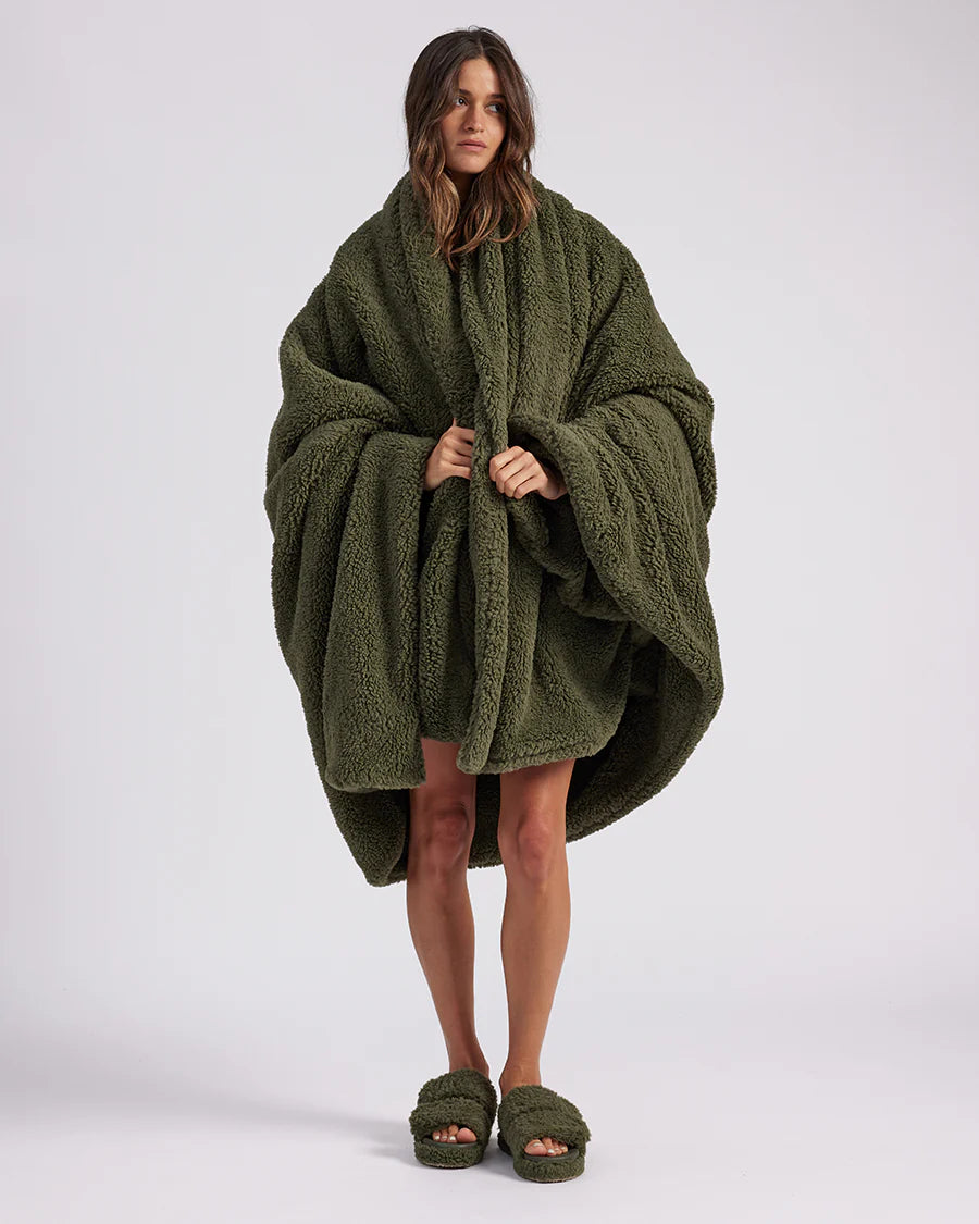 woman standing with green fluffy throw blanket around her 