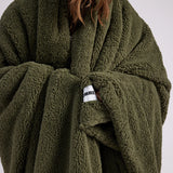 up close shot of woman standing with green fluffy throw blanket around her 