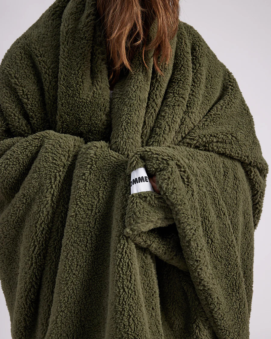 up close shot of woman standing with green fluffy throw blanket around her 