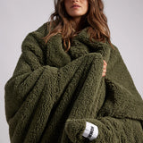 woman standing with green fluffy throw blanket around her 