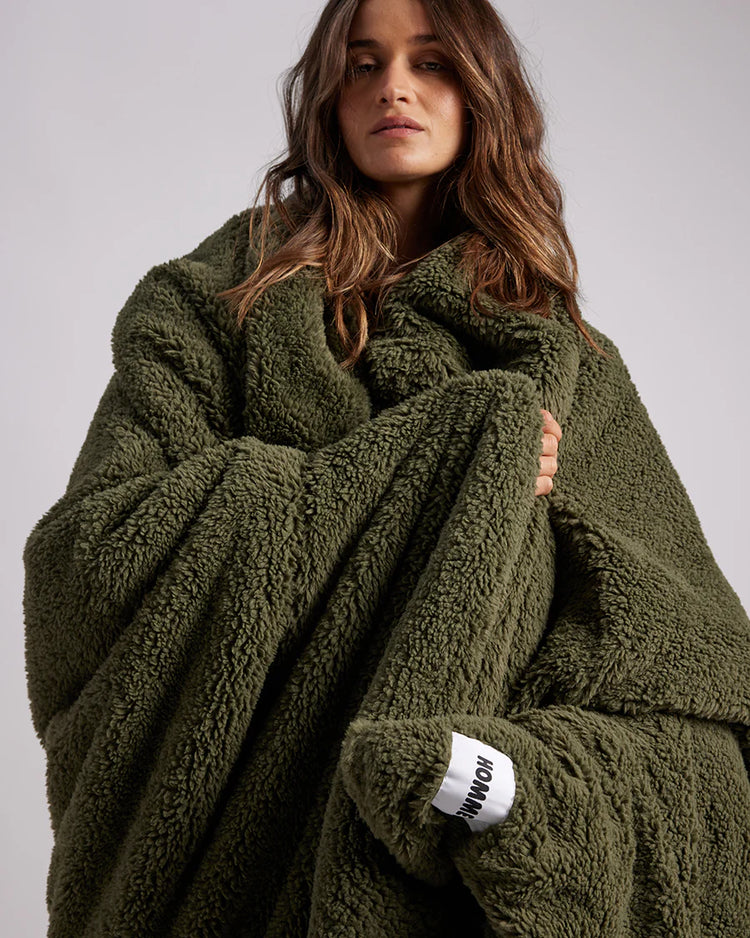 woman standing with green fluffy throw blanket around her 