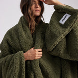 woman standing with green fluffy throw blanket around her 