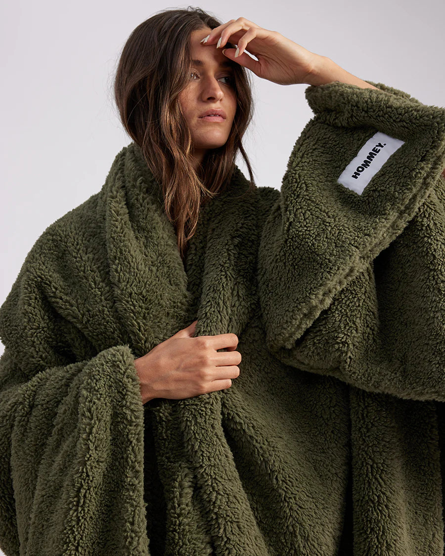 woman standing with green fluffy throw blanket around her 