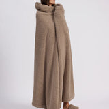 girl wrapped up with a beige throw blanket standing