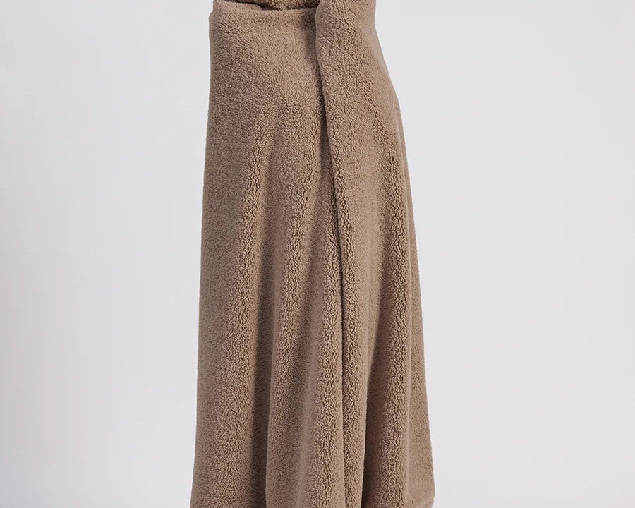 girl wrapped up with a beige throw blanket standing