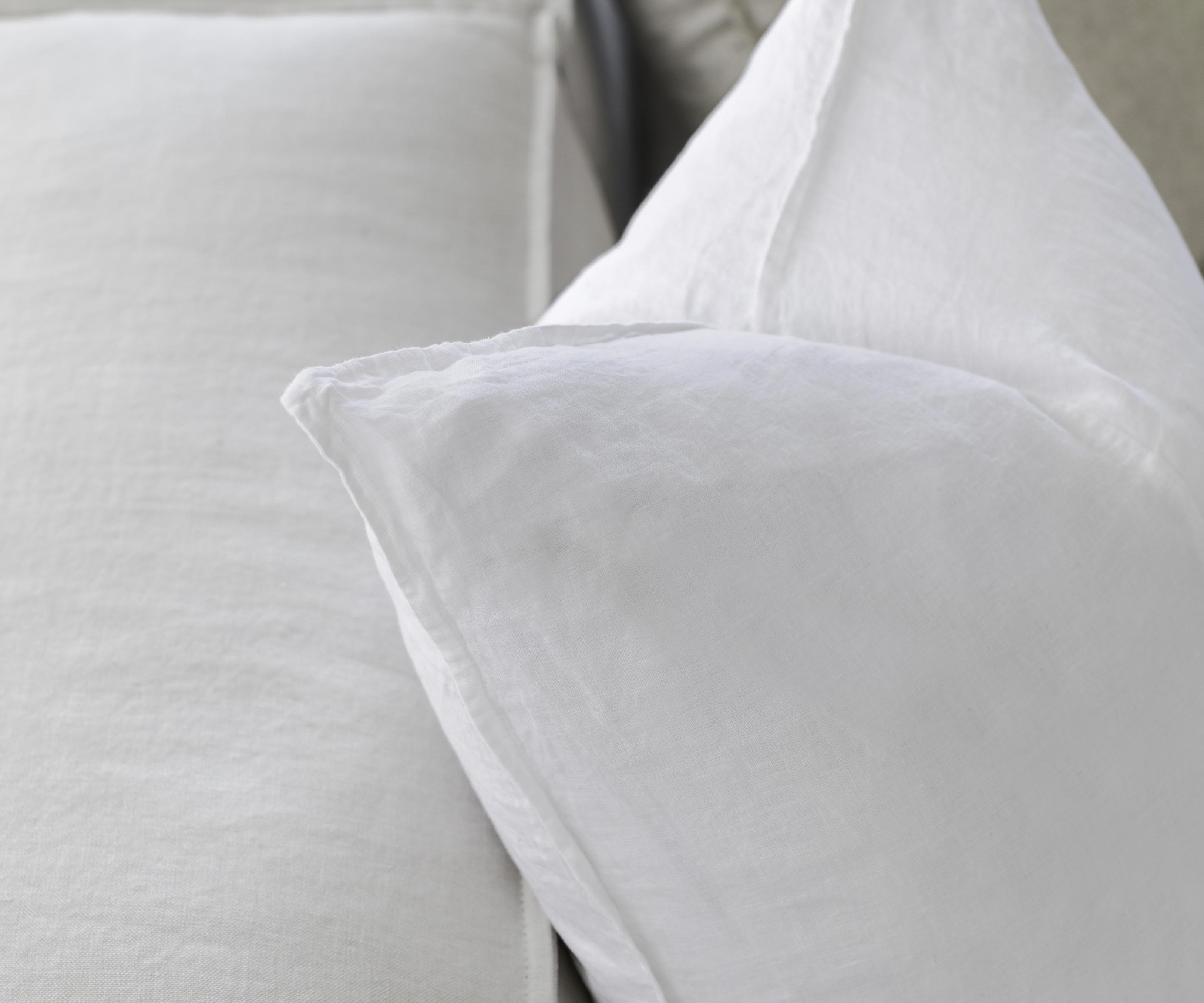 up close picture of white linen cushions sitting on a couch