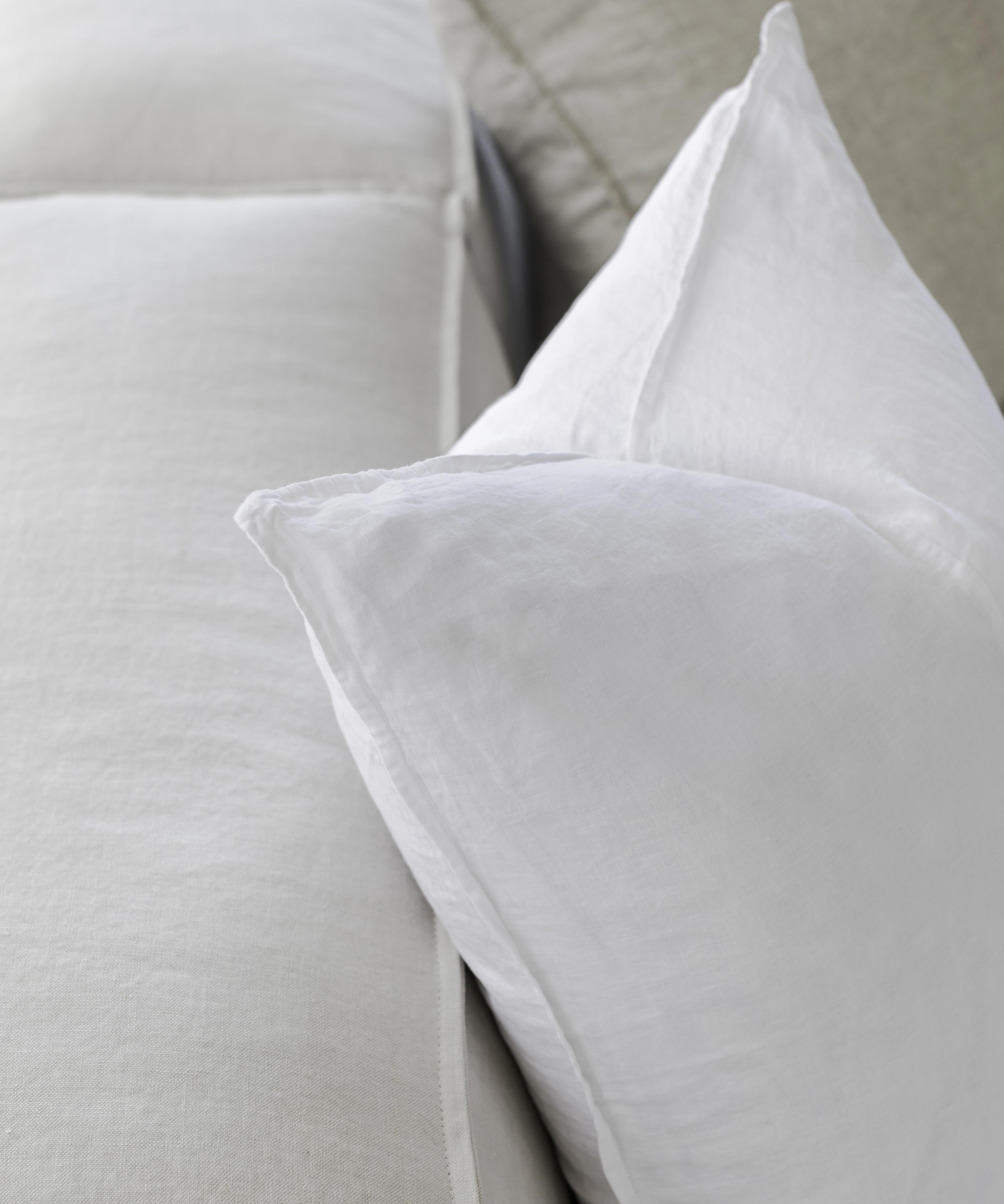 up close picture of white linen cushions sitting on a couch