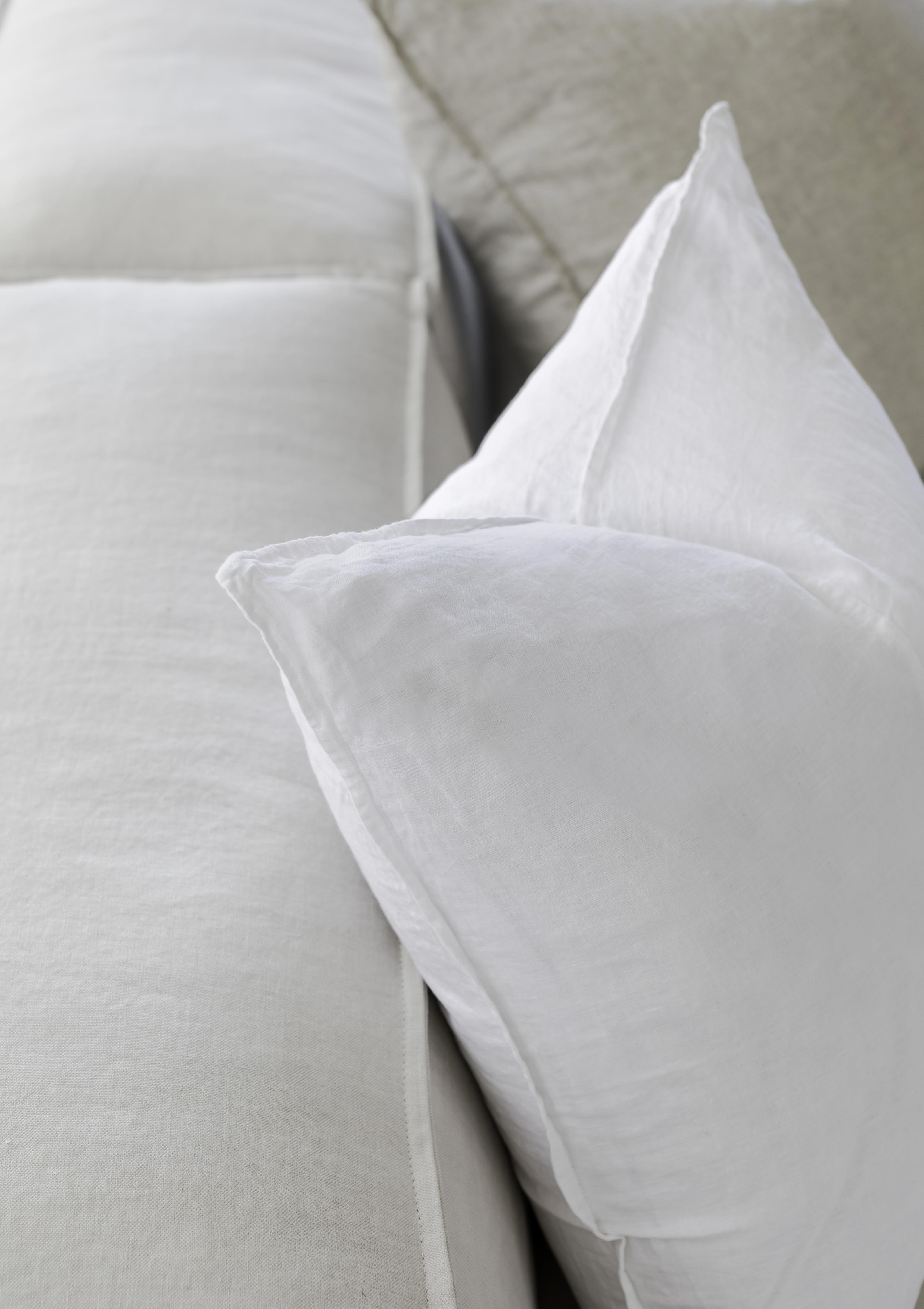 up close picture of white linen cushions sitting on a couch