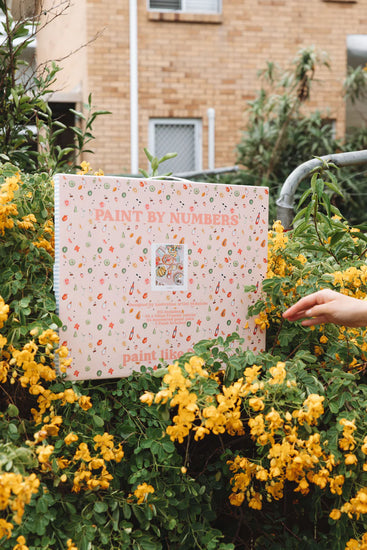 artwork in packaging sitting in flower bush