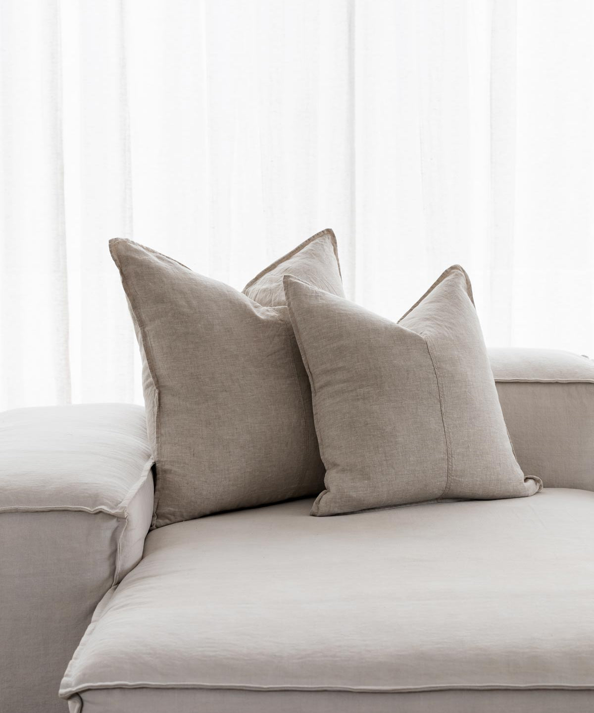 beige linen cushions sitting on white couch