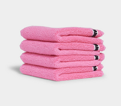pink face washer towels sitting in stack on white background