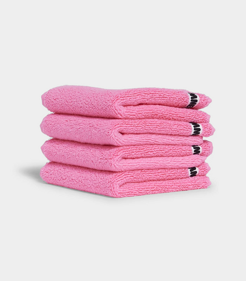 pink face washer towels sitting in stack on white background