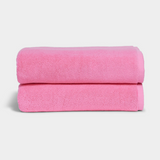 pink towel sitting in stack on white background
