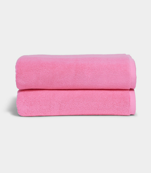 pink towel sitting in stack on white background