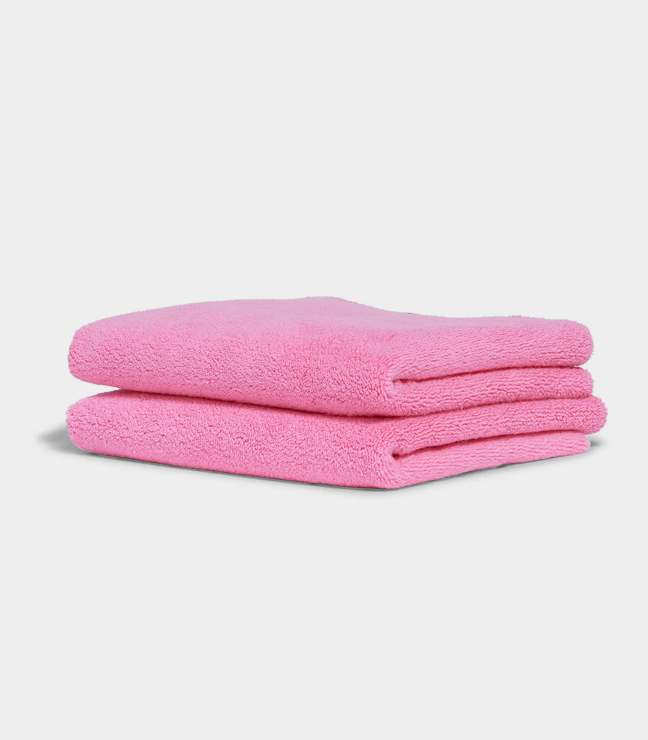 pink hand towel sitting in stack on white background